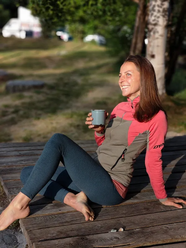 Helena Fiechter, Therapeutin für Fussreflexzonenmassage, sitzt lächelnd auf einem Holzsteg in der Natur