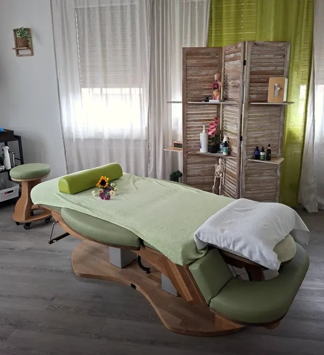 Massageliege für die Fussreflexzonenmassage vor einem Holzparavent